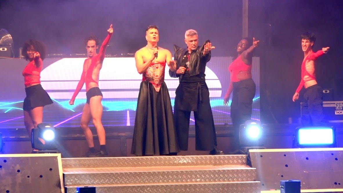 Eugin Vita in a red corset and Lui da Motta in black leather, the four dancers pointing at the crowd under blue light.