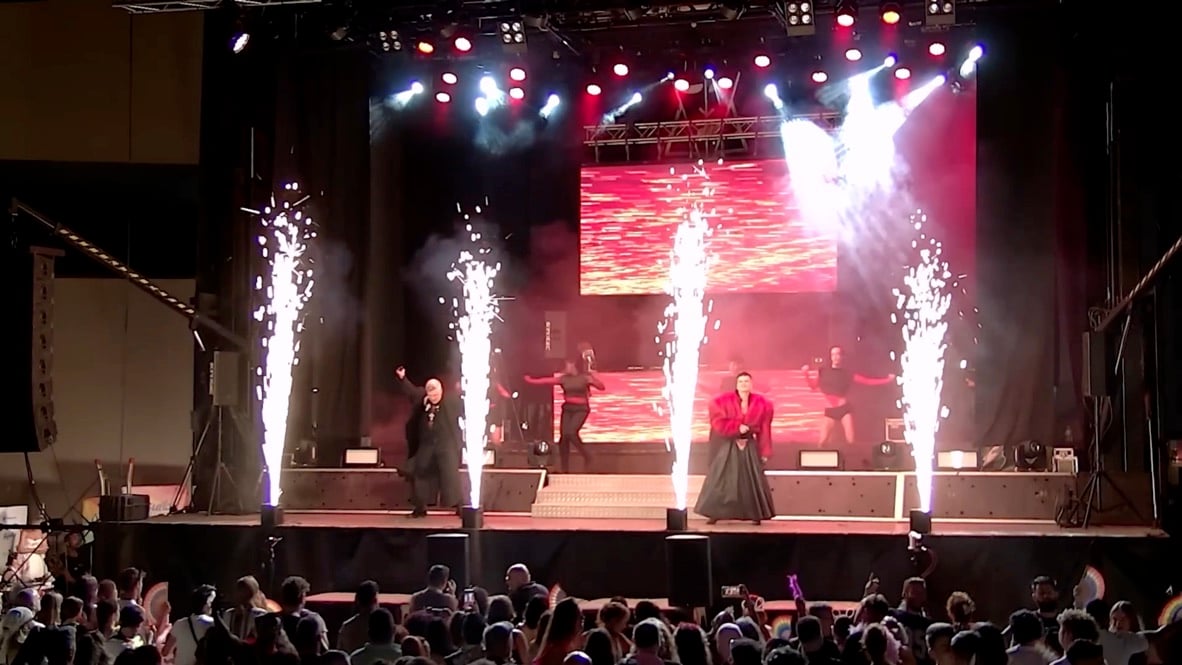 Wide shot from the crowd: pyro, screens and the full stage.